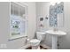 Stylish powder room featuring a pedestal sink, decorative mirror, and a street view from the window at 10993 Liberation Trce, Noblesville, IN 46060