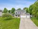 A charming two-story home showcases a stone accents, a three-car garage, and a well-manicured lawn in a suburban setting at 113 Spring Creek Ct, Noblesville, IN 46062