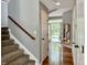 A bright hallway with hardwood floors, a staircase, and a view of the front yard through the open door at 12044 Bird Key Blvd, Fishers, IN 46037
