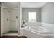 Bright bathroom featuring a glass shower, large tub with tile surround, and a window for natural light at 12331 Chiseled Stone Dr, Fishers, IN 46037