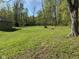 A green backyard featuring mature trees and lawn, side of a house and firepit at 1340 Apache Trl, Martinsville, IN 46151