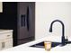 Close-up of a kitchen with a sleek black faucet, a modern countertop, and a matching black refrigerator at 1730 Hoyt Ave, Indianapolis, IN 46203