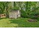Backyard featuring shed, a well-maintained lawn, surrounding trees, and a charming fire pit at 1802 E 66Th St, Indianapolis, IN 46220
