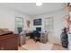 A home office with wood desk and shelving, large area rug, and natural light from two windows at 1802 E 66Th St, Indianapolis, IN 46220