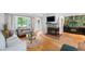 Open-concept living room with wood floors, a fireplace, large window, and open access to the dining area at 2120 Wynnedale Rd, Indianapolis, IN 46228