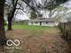 Large, grassy backyard with a white single-story home in the background, surrounded by trees at 4108 Steinmetz Dr, Indianapolis, IN 46254