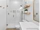 Bright bathroom featuring a walk-in shower with glass door, stylish tile, and floating shelves for added storage at 4428 Maldenhair Dr, Indianapolis, IN 46239