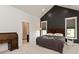Modern bedroom with dark accent wall, wood headboard, and neutral carpet at 4457 E County Road 850 N, Pittsboro, IN 46167