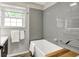Modern bathroom featuring grey subway tile, a window, and a white bathtub with handrails at 5104 Carvel Ave, Indianapolis, IN 46205