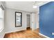 Bedroom with blue accent wall, hardwood floors, and a closet with open doors at 5104 Carvel Ave, Indianapolis, IN 46205