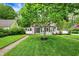 Charming two-story home with a well-manicured lawn, mature trees, and a welcoming walkway leading to the front door at 5104 Carvel Ave, Indianapolis, IN 46205