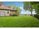 Large backyard with lush green lawn, mature landscaping, and an outdoor deck with pergola at 5786 E Fall Creek Pkwy N Dr, Indianapolis, IN 46226