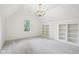Charming bedroom showcasing a chandelier, built-in shelves, neutral carpet, and a bright window at 5786 E Fall Creek Pkwy N Dr, Indianapolis, IN 46226