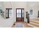 Bright foyer featuring a wood door, light wood floors, staircase with dark railing, and a stylish mirror at 5786 E Fall Creek Pkwy N Dr, Indianapolis, IN 46226