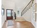 Bright foyer featuring a wood door, light wood floors, staircase with dark railing, and a stylish mirror at 5786 E Fall Creek Pkwy N Dr, Indianapolis, IN 46226