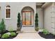 Close-up of front entrance with arched wood door, black mulch, and manicured greenery around the front walkway at 5786 E Fall Creek Pkwy N Dr, Indianapolis, IN 46226