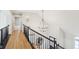 Upstairs hallway with hardwood flooring and black metal railing featuring lighting at 5786 E Fall Creek Pkwy N Dr, Indianapolis, IN 46226