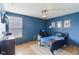 A bedroom with blue painted walls, a ceiling fan, hardwood floors and a large window letting in natural light at 6078 Hardwick Dr, Whitestown, IN 46075