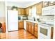 Kitchen with hardwood floors, white appliances, and wood cabinetry at 6126 Rucker Rd, Indianapolis, IN 46220