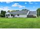 Wide backyard showing the white brick house with well-kept lawn, mature landscaping, and a fence at 6190 S 425 W, Pendleton, IN 46064