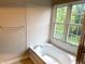 Bathroom featuring white tiled wall, large bright window and soaking tub at 6242 Carrington Dr, Indianapolis, IN 46236