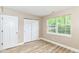 Well-lit bedroom with wood-look flooring, a closet with sliding doors, and a window with natural light and view at 6471 Hunters Green Pl, Indianapolis, IN 46278