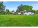 Spacious backyard featuring a well-maintained lawn, established garden beds, and mature trees at 7316 Lesley Ave, Indianapolis, IN 46250