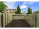 View of fenced-in backyard with mulch bed and glimpse of house behind trees, creating a private outdoor space at 7334 Country Brook Dr, Indianapolis, IN 46260