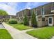 Exterior view of townhomes with lush green lawns, sidewalks, and mature landscaping at 7334 Country Brook Dr, Indianapolis, IN 46260