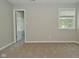 Neutral bedroom featuring plush carpeting, a window with blinds, and a white door with a view into another room at 8354 Fieldfare Way, Indianapolis, IN 46237