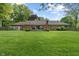 Expansive backyard featuring a brick home, wooden deck, green lawn, and mature trees, perfect for outdoor living at 9885 Oakleaf Way, McCordsville, IN 46055