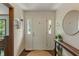 Bright foyer with a white door, wood floors, and stylish decor, including a round mirror at 9885 Oakleaf Way, McCordsville, IN 46055