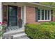 Close up of the front entrance, with a brick facade, a colorful door, and manicured landscaping at 9885 Oakleaf Way, McCordsville, IN 46055