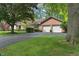 Brick home featuring an attached two-car garage and an asphalt driveway with mature trees and a lawn at 9885 Oakleaf Way, McCordsville, IN 46055