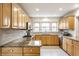 Bright kitchen with granite countertops, a tile backsplash, stainless appliances, and blond wood cabinetry at 100 Wellington Rd, Indianapolis, IN 46260