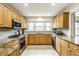 Spacious kitchen with natural wood cabinets, granite countertops, stainless steel appliances, and bright lighting at 100 Wellington Rd, Indianapolis, IN 46260