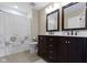 Bathroom features double sink vanity with dark cabinets and a shower-tub combination with a leaf-patterned curtain at 11872 Traymoore Dr, Fishers, IN 46038