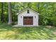 Detached one car garage with wooden doors in a lush backyard at 13300 Fairwood Dr, McCordsville, IN 46055