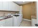 Functional laundry room with white cabinets, sink, countertop, and modern washer/dryer at 13300 Fairwood Dr, McCordsville, IN 46055