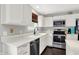 Well-lit kitchen features stainless steel appliances, white cabinetry, a dark faucet, and dark hardwood floors at 14638 Deerwood Dr, Carmel, IN 46033