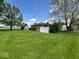 Expansive green backyard featuring mature trees and a charming white fence accenting the home's exterior at 1925 W State Road 32, Lebanon, IN 46052