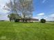 Expansive backyard featuring a well-maintained lawn, mature trees, and view of home's exterior with inviting deck at 1925 W State Road 32, Lebanon, IN 46052