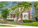 Beautiful red brick home featuring a covered front porch, mature trees, manicured lawn, and professional landscaping at 2037 Stanhope St, Carmel, IN 46032