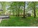 Lush backyard with mature trees, green grass, wooden fence and a shed offers a private outdoor oasis at 3333 Melbourne S Rd, Indianapolis, IN 46228