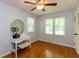 Bright bedroom with hardwood floors, ceiling fan, and vanity with large round mirror at 3333 Melbourne S Rd, Indianapolis, IN 46228