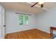 A serene bedroom featuring hardwood floors, a ceiling fan, and a window with backyard views at 3333 Melbourne S Rd, Indianapolis, IN 46228
