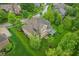 Aerial view of a home with a brick exterior, well-manicured lawn, mature trees, and a back deck at 3744 Abney Point Dr, Carmel, IN 46077