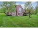 A large backyard with lush green lawn, mature trees, and the back of a brick house with a deck at 3744 Abney Point Dr, Carmel, IN 46077