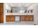 Double vanity in the main bathroom with warm wood cabinets and large mirror at 3823 Brigade Cir, Carmel, IN 46032