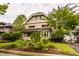 Lovely two-story brick house with manicured landscaping, including trees, shrubs, and colorful flowers at 3840 N Washington Blvd, Indianapolis, IN 46205
